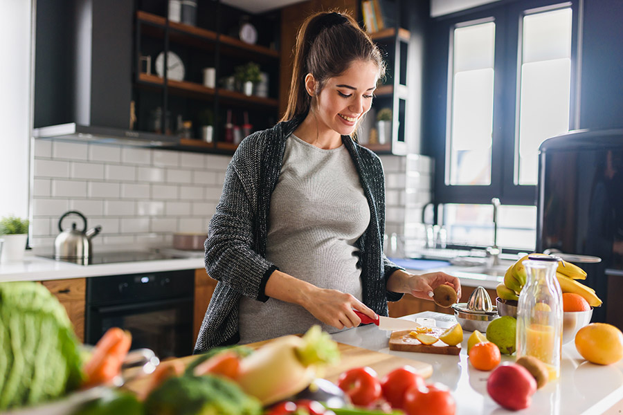 Schwangere Frau beim Kochen in der Küche