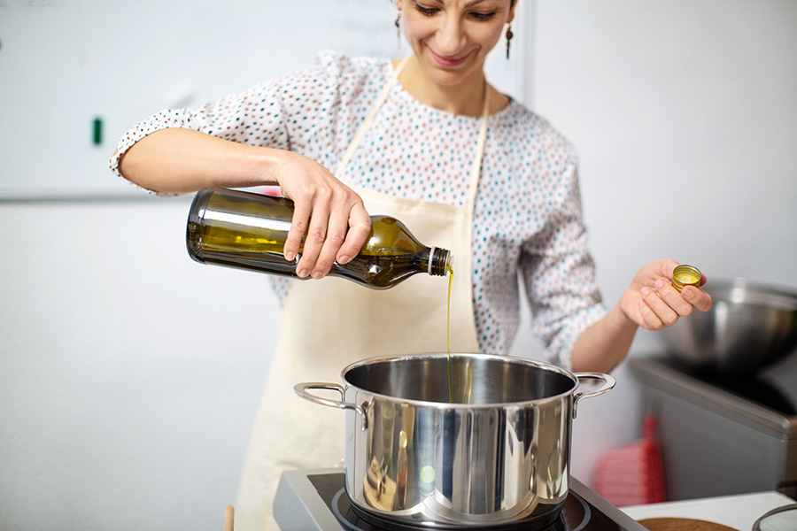 Eine Frau schüttet Öl in einen Kochtopf