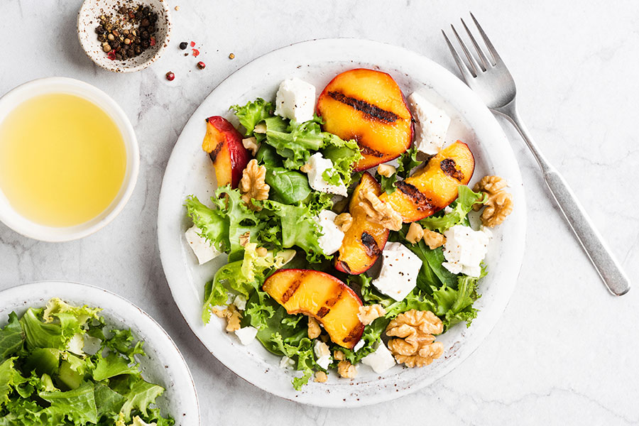 Teller mit Salat, Obst, Schafkäse und Walnüssen